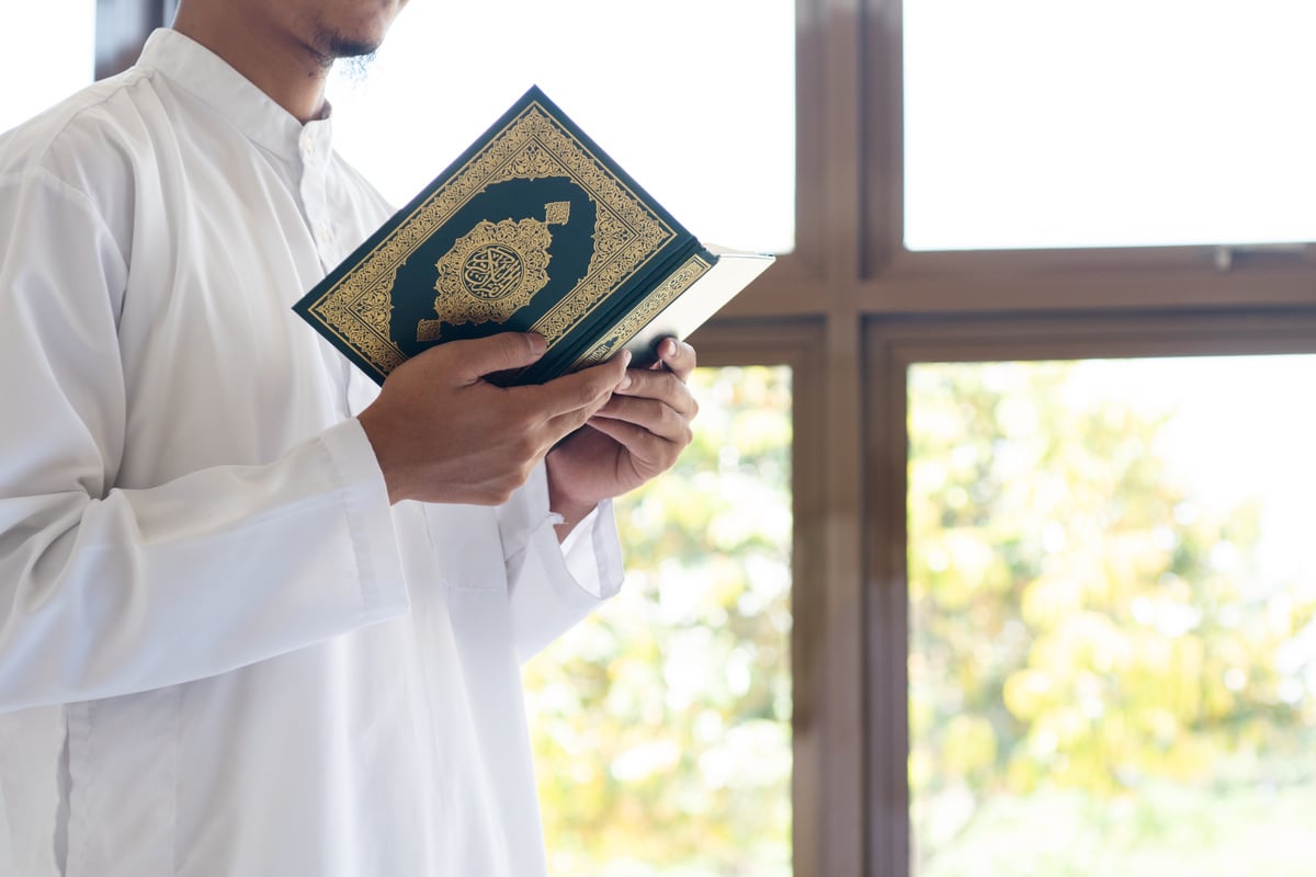 Muslim man reading holy Quran. Quran with arabic text meaning of Al Quran. Islamic concept background